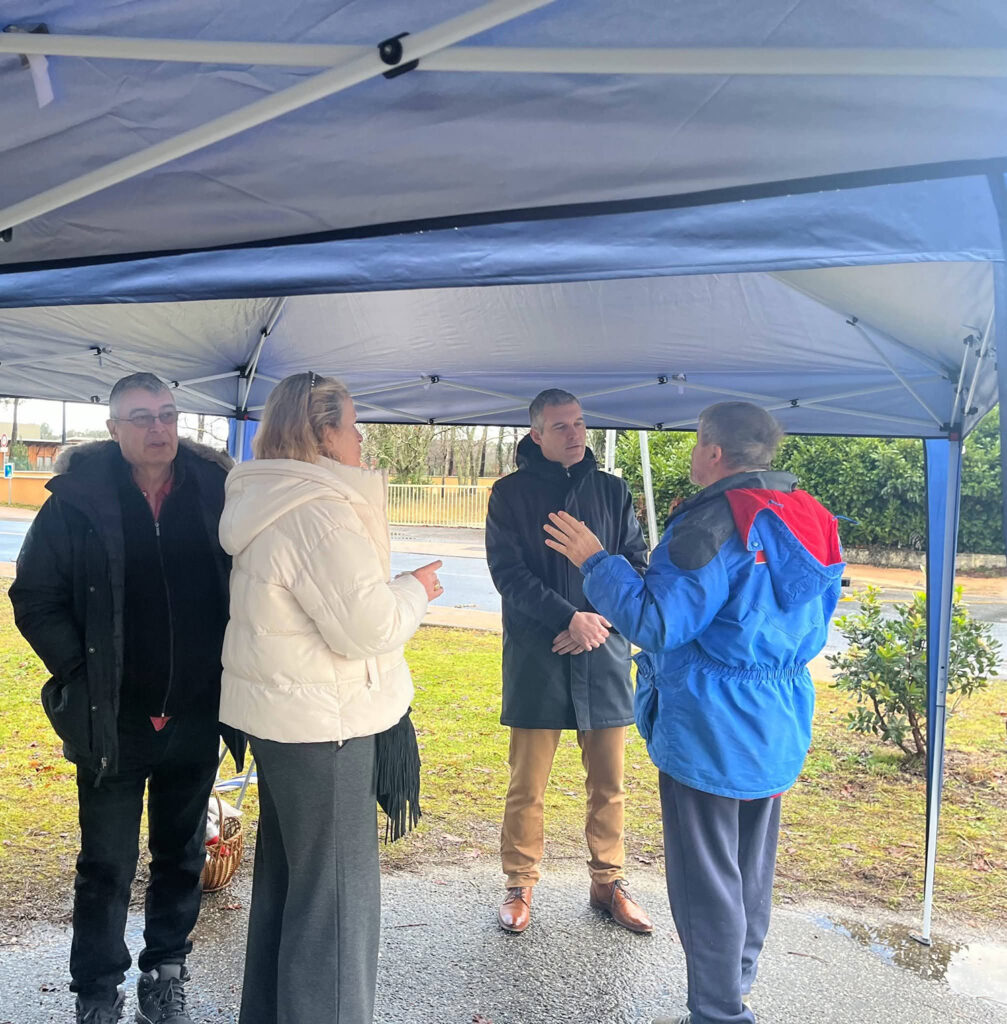Discussion entre habitants sous un barnum lors de la réunion de quartier